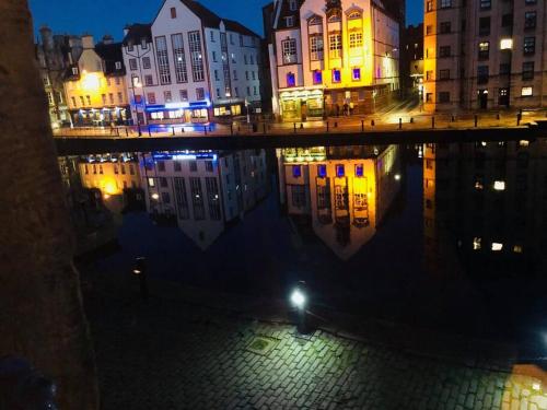 a city at night with a reflection in the water at Vibrant Apartment at The Shore in Leith in Edinburgh