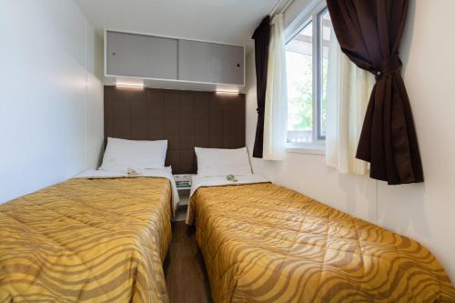 two beds in a small room with a window at Camping Village Garden Paradiso in Cavallino-Treporti