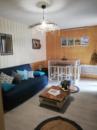 a living room with a blue couch and a table at Studio RDC 4-5 pers pied des pistes in Chaillol