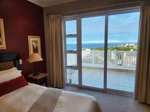 Schlafzimmer mit einem Bett und einem großen Fenster mit einem Balkon in der Unterkunft Pinnacle Point Golf Estate - Golf Villa 10-1 in Mossel Bay