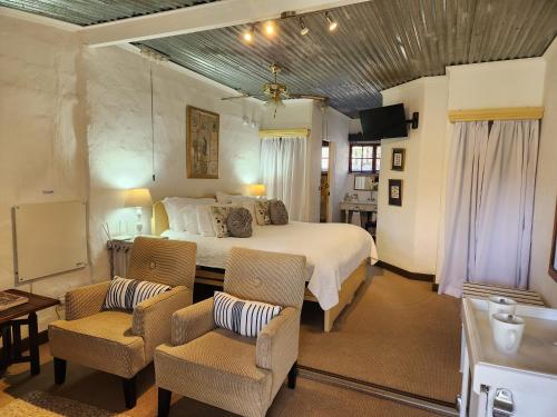 a bedroom with a large bed and two chairs at Cleopatra Mountain Farmhouse in Fort Nottingham