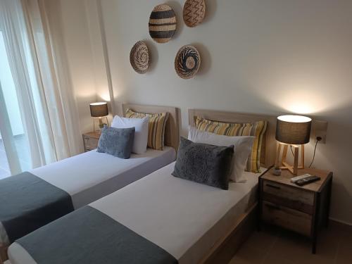 two beds in a bedroom with two lamps and pillows at Amare Luxury Living in Volos