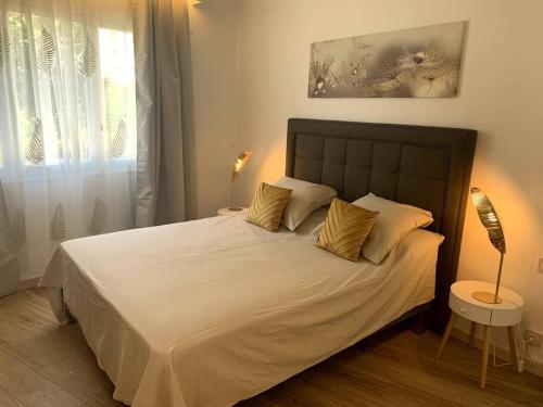 - une chambre dotée d'un grand lit avec des draps blancs et des oreillers en or dans l'établissement Cannes : Appartement rénové proche plage, à Cannes