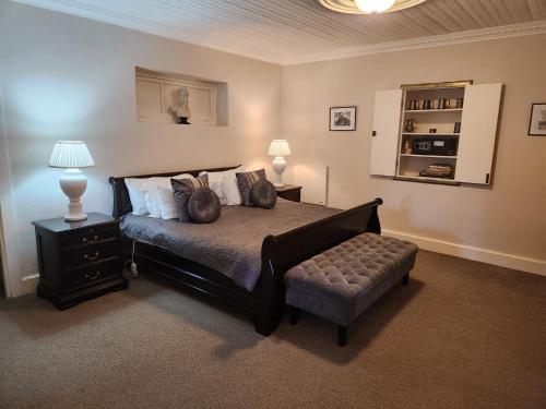 a bedroom with a bed with a ottoman and a lamp at Cleopatra Mountain Farmhouse in Fort Nottingham