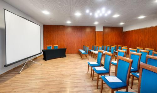 a conference room with blue chairs and a white screen at Hunguest Bük - ex Répce és Répce Gold in Bük