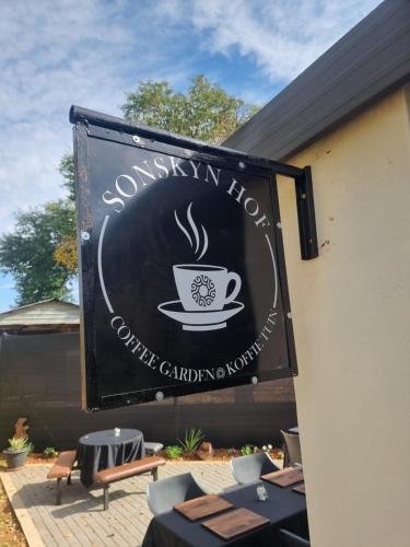 een bord voor een café met een kopje koffie erop bij Sonskyn Hof Guest House / Gastehuis in Jan Kempdorp