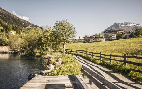a bridge over a river next to a fence at Vital Hotel Ortlerspitz in San Valentino alla Muta