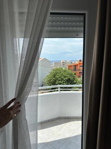 a person looking out a window at a balcony at Apartmani Sunce in Bar