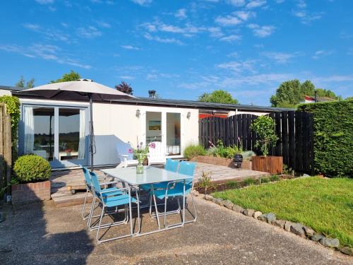 a table with chairs and an umbrella in a garden at Vakantiewoning Goedgelegen MB01 in Middelburg