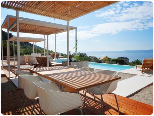 a wooden table and chairs on a patio with a pool at Modern Mediterranean Oasis - Villa Bolka in Bol