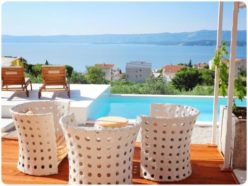a table and chairs on a deck with a view of a pool at Modern Mediterranean Oasis - Villa Bolka in Bol