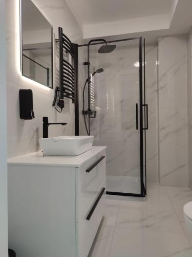 a white bathroom with a shower and a sink at Apartamenty Amadeus Mare in Rowy