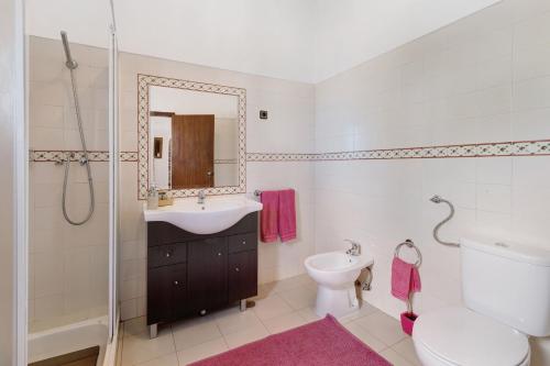 y baño con lavabo, aseo y espejo. en Casa Castelão, en Palmela