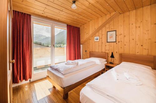 een slaapkamer met 2 bedden en een groot raam bij Aquila Dolomites Residence in Ortisei