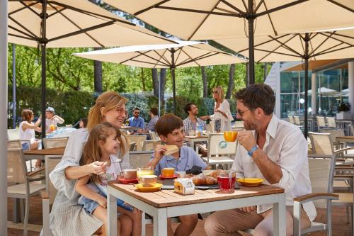 a family sitting at a table eating at a restaurant at Camping Village Garden Paradiso in Cavallino-Treporti
