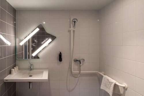 a white bathroom with a shower and a sink at ibis budget Saint-Étienne Centre Gare Châteaucreux in Saint-Étienne
