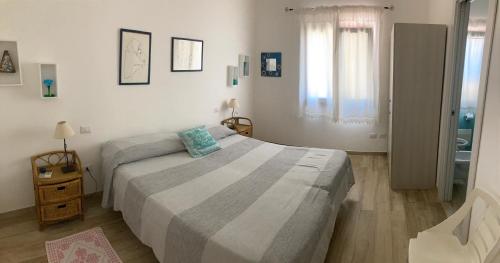 a white bedroom with a bed and a window at Punta Sirenella in Olbia