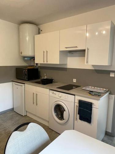 une cuisine avec des armoires blanches et une machine à laver dans l'établissement Studio RdC parking privé gratuit, à Doué-la-Fontaine