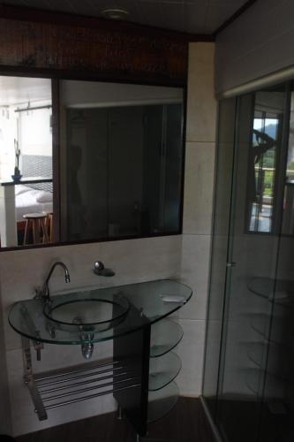 a bathroom with a glass sink and a mirror at Toca da Tulipa in Paraty