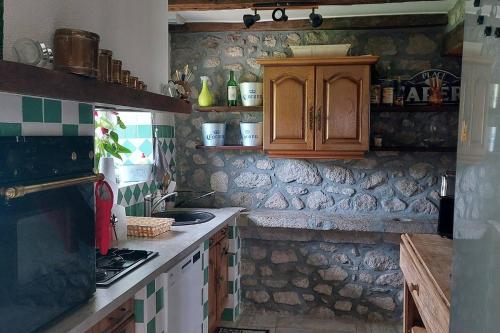 - une cuisine avec des placards en bois et un mur en pierre dans l'établissement Maison la Taissotine, à Leucamp