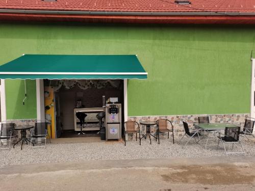 a green building with tables and chairs in front of it at La Nera in Sasca Română