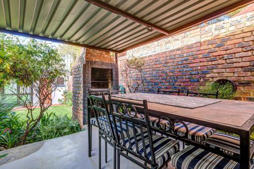 a patio with a brick wall and a wooden table and chairs at Lavender Villa No loadshedding in Kempton Park