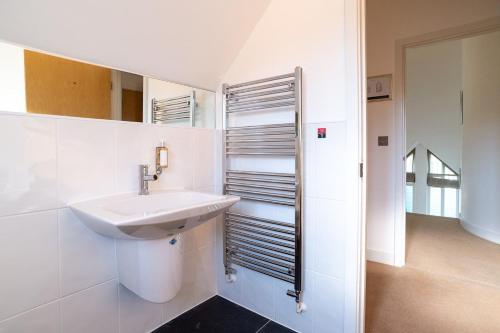 a white bathroom with a sink and a mirror at Trewhiddle Retreat V11 by Together Travel - Luxury 4-Bedroom Villa in St Austell