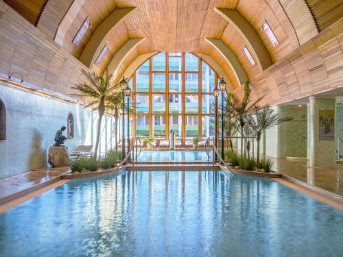 una gran piscina en un edificio con un gran techo en Hotel Carbona Thermal Spa en Hévíz