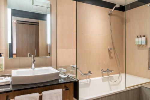 bagno con lavandino, vasca e specchio di Le Parchamp, a Tribute Portfolio Hotel, Paris Boulogne a Boulogne-Billancourt