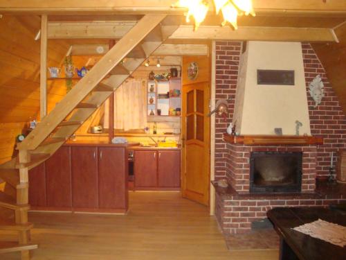 a living room with a kitchen and a fireplace at LESNA CHATA in Zagórnik