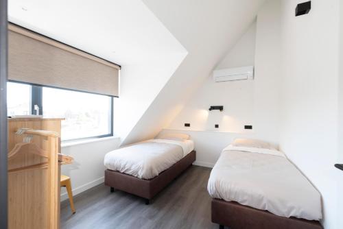 2 Betten in einem Zimmer mit weißen Wänden in der Unterkunft De Zuivelhandel in Petten