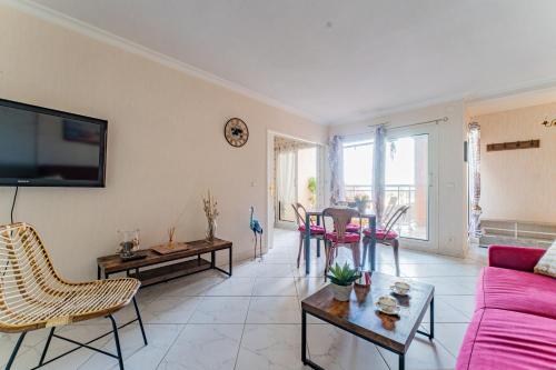 un salon avec un canapé rose et une table dans l'établissement La Brise Marine - Appt avec balcon 50m de la plage, à Arcachon