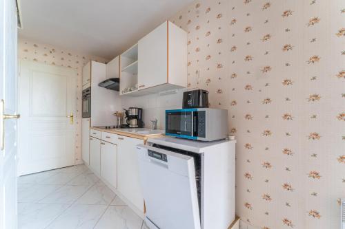 a kitchen with white cabinets and a microwave at La Brise Marine - Appt avec balcon 50m de la plage in Arcachon