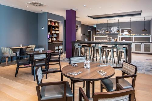 um restaurante com mesas e cadeiras e um bar em Premier Inn Stuttgart City Centre em Estugarda
