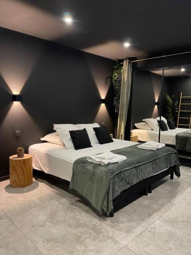 een slaapkamer met 2 bedden en een zwarte muur bij Spa & Love Exotic - Balnéo - Sauna - Parking in Clermont-Ferrand