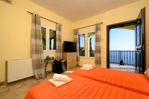 a bedroom with two beds with orange sheets and a television at Nisos Sunset Apartments Agios Gordios in Corfu Town