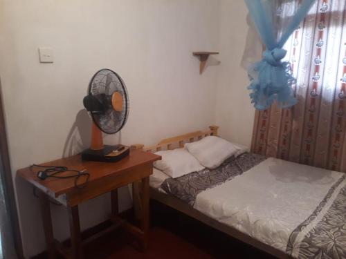 a bedroom with a bed and a desk with a fan at SUPER SUN HOMESTAY in Katugastota