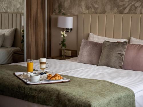 a breakfast tray on a bed with a tray of food at Hotel Carbona Thermal Spa in Hévíz