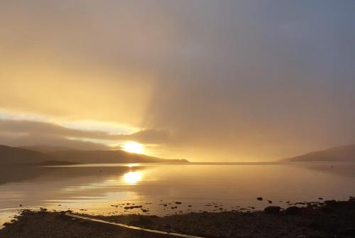 a sunset over a body of water with the sun setting at Burnside in Tighnabruaich