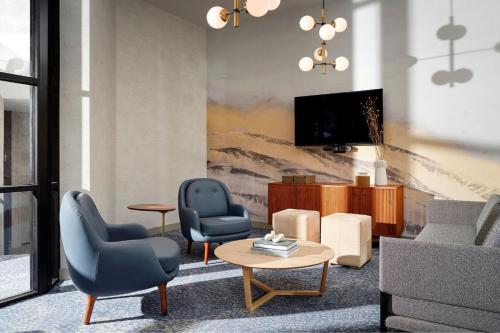 a living room with two chairs and a tv at Sheraton Grand Rapids Airport Hotel in Grand Rapids