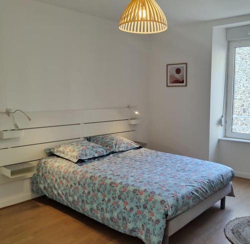 a bedroom with a bed and a lamp and a window at Le Corsaire appartement centre ville 500 mètres des plages in Granville