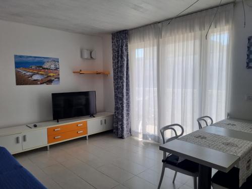 sala de estar con TV y mesa de comedor en Appart-Hotel Holiday, en Lignano Sabbiadoro