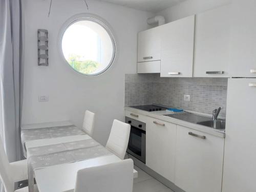 a kitchen with white cabinets and a table and chairs at Appart-Hotel Holiday in Lignano Sabbiadoro