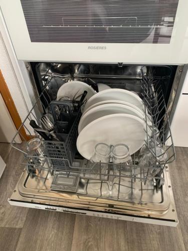 an open dishwasher with dishes and plates in it at L'écrin du Bachat Chamrousse in Chamrousse