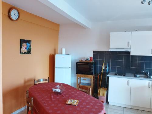 a kitchen with a table and a refrigerator and a clock at Le Papillon Bleu in Bouillante