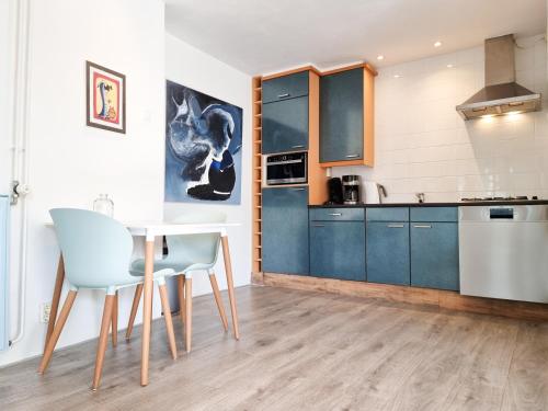 a kitchen with blue cabinets and a table and chairs at Vakantiewoning Goedgelegen MB01 in Middelburg