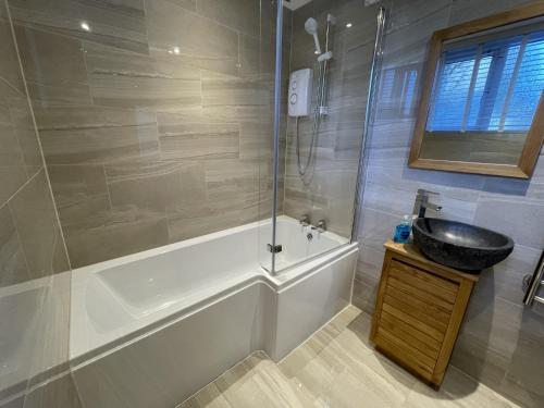 a bathroom with a tub and a sink and a shower at Triple Deck Cottage - 2mins from Mevagissey Harbour in Mevagissey