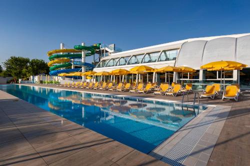 una piscina con sillas amarillas y un tobogán de agua en Camping Village Garden Paradiso en Cavallino-Treporti