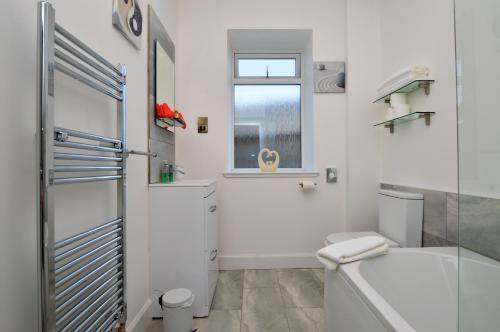 a bathroom with a tub and a toilet and a window at Burnside in Tighnabruaich