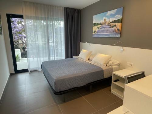 a bedroom with a bed and a large window at Hotel C31 in Castelldefels
